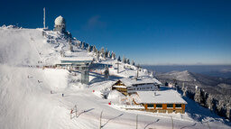Der schneebedeckte Abergipfel mit Wetterstation und verschiedenen Gebäuden.