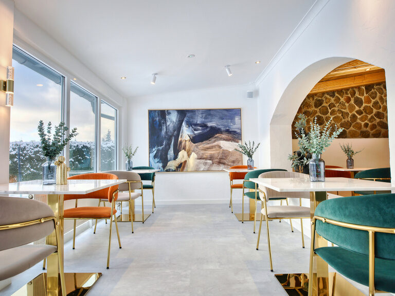 Ein stilvoll möblierter Loungebereich im Hotel Kronberg in Bodenmais mit großen Fenstern, die viel Licht einlassen.