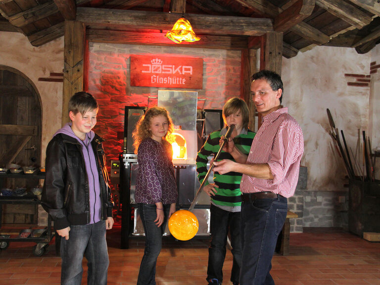 Ein Glasbläser zeigt ein paar Kindern sein Handwerk.
