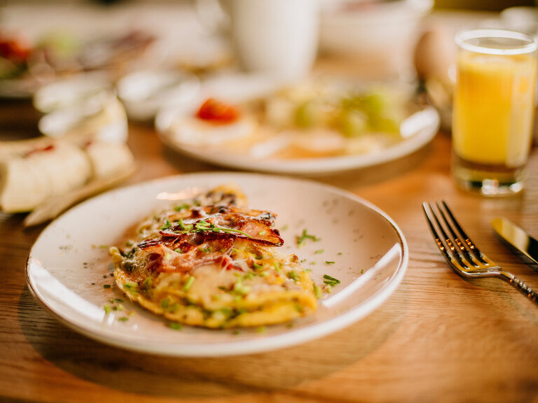 Schön garnierter Frühstücksteller mit Omelett auf einem Holztisch im Hotel in Bodenmais.