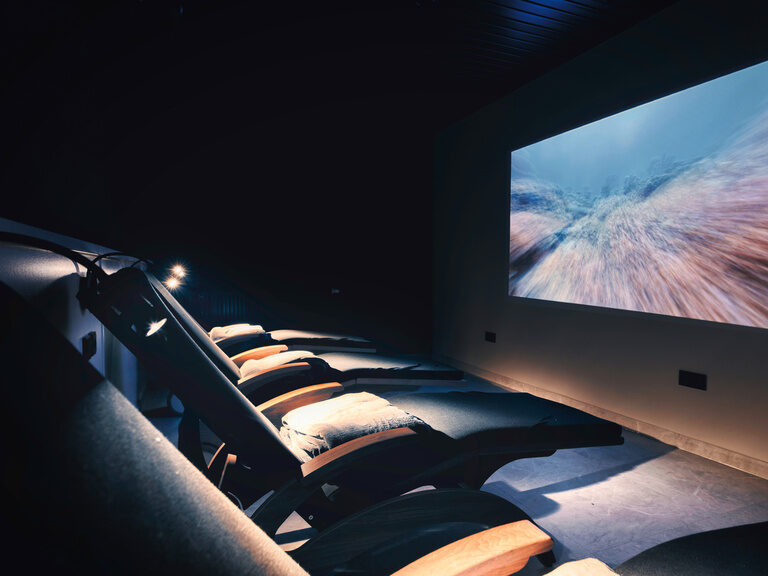 Gemütliche Sitzmöglichkeiten und Leinwand im Kino des natura Hotel Bodenmais.