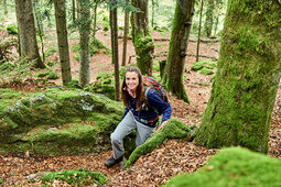 Eine Frau steigt einen Hang in einem Waldstück des Bayerischen Waldes hoch